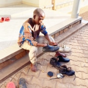 Former street child from Kampala cleaning his shoes
